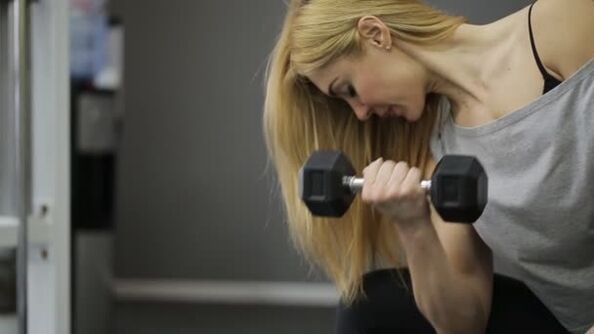 La fille effectue un exercice d'haltères